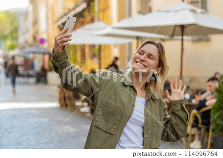 Woman blogger taking selfie on smartphone, communicating video call online with subscribers in city Woman blogger taking selfie on smartphone, communicating video call online with subscribers in city 114096764