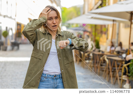 Scared young woman worrying to be punctual with anxiety checking time on watch running late to work 114096778