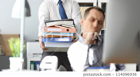 Man carrying big pile of documents to unhappy colleague Man carrying big pile of documents to unhappy colleague 114096936