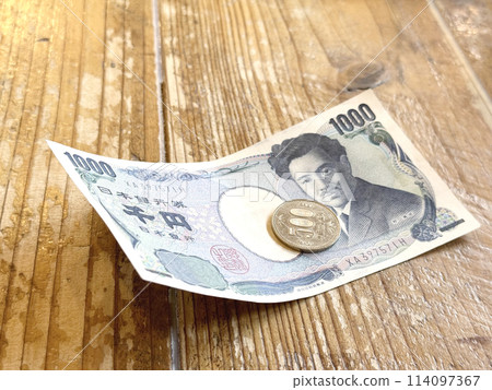 1,000 yen bill and 500 yen coin on a wooden table 114097367