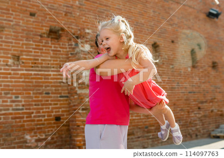 Blonde little girl with cochlear implant playing with her mother outdoor. Hear impairment deaf and health concept. Disability and inclusion. Copy space 114097763