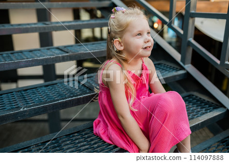 Child with hearing problem and cochlear implant dance in street, deaf kid began to hear. Hearing loss in childhood and treatment concept. Copy space and empty place for text. Inclusion and disability 114097888