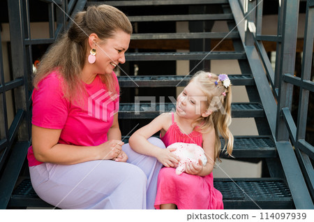 Child girl with cochlear implant with her mother spend time outdoor. Hear impairment and deaf community concept. Deaf and health concept. Disability and inclusion. Copy space Child girl with cochlear implant with her mother spend time outdoor. Hear impairment and deaf community concept. Deaf and health concept. Disability and inclusion. Copy space 114097939