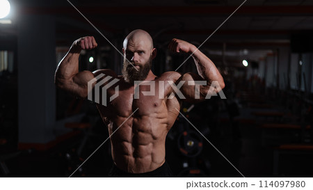 Caucasian bald man posing in the gym. Caucasian bald man posing in the gym. 114097980