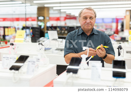 Elderly male customer looking for a deal on smart watches in big electronics store Elderly male customer looking for a deal on smart watches in big electronics store 114098079