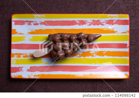 chocolate dessert with nuts on a stick on a striped plate. top view 114098142