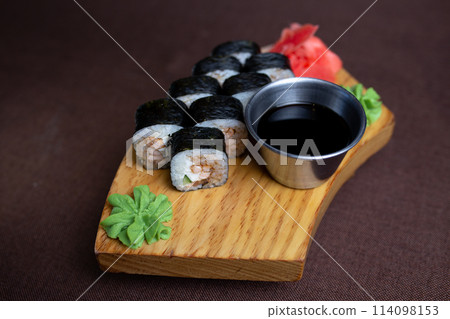 rolls with tuna, sauce and wasabi on a wooden stand 114098153