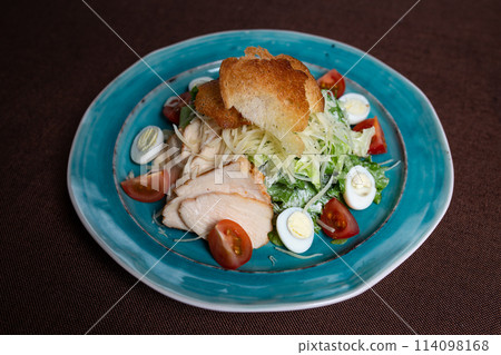 Greek salad with chicken and breadcrumbs on a blue plate Greek salad with chicken and breadcrumbs on a blue plate 114098168