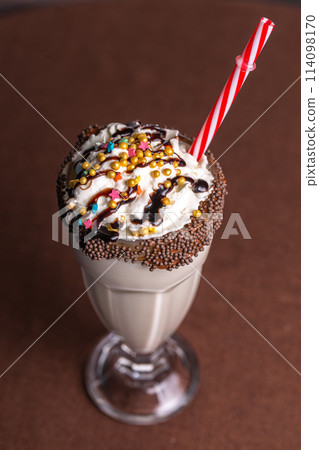 sweet milkshake with a tube on a brown background sweet milkshake with a tube on a brown background 114098170