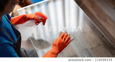 Asian woman cleaning the glass table in the apartment. Cleaning staff maintain cleanliness in with towel and spray detergent Asian woman cleaning the glass table in the apartment. Cleaning staff maintain cleanliness in with towel and spray detergent 114099154
