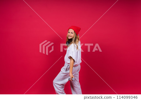Kid girl doing fitness exercises with dumbbells on red background Kid girl doing fitness exercises with dumbbells on red background 114099346