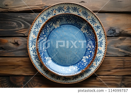 Two empty decorative blue and white plates with pattern top view on wooden brown background, mock up for decor or montage 114099787