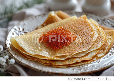 Homemade thin pancakes decorated with red caviar on white plate on cozy background, festive dish for maslenitsa week Homemade thin pancakes decorated with red caviar on white plate on cozy background, festive dish for maslenitsa week 114100149
