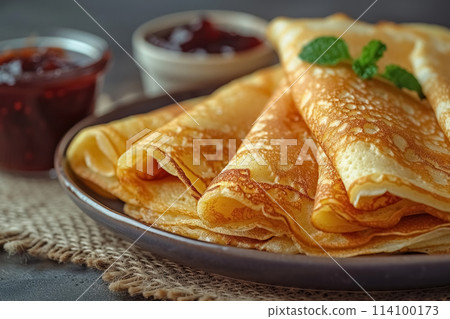 Several of homemade thin pancakes on grey plate with jam, tasty treat for festive maslenitsa week 114100173
