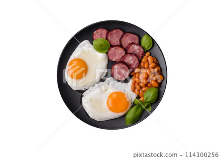 English breakfast with fried eggs, bacon, beans, tomatoes, spices and herbs 114100256