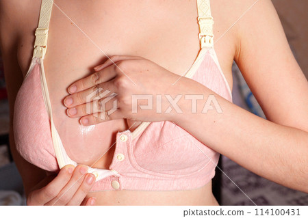 Close Up of pregnant women having painful feelings in breast. Woman checking her breast for cancer. the girl smears the inflamed breast with a cream from mastitis 114100431