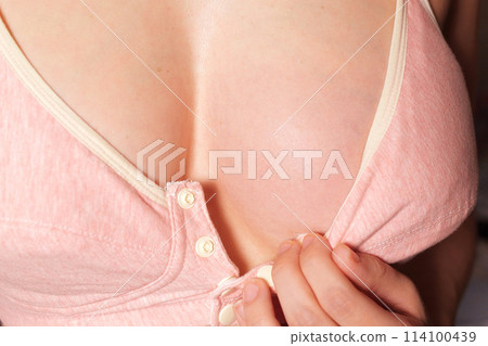 Close Up of pregnant women having painful feelings in breast. Woman checking her breast for cancer. the girl smears the inflamed breast with a cream from mastitis 114100439