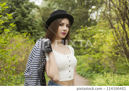Young adult lady outdoors. Healthy woman with fresh clean skin and long brown hair in black hat.  114100481
