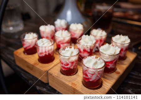 Group cheers with shot glasses of Paulaner hefeweizen wheat beer at fun event 114101141