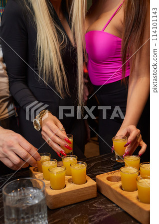 Group cheers with shot glasses of Paulaner hefeweizen wheat beer at fun event Group cheers with shot glasses of Paulaner hefeweizen wheat beer at fun event 114101143