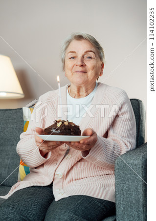 Cheerful smiling mature aged senior woman holds birthday cake and blowing a candle, celebrates a birthday at home and laughs, feeling happy. Enjoying retirement lifestyle. Vertical card Cheerful smiling mature aged senior woman holds birthday cake and blowing a candle, celebrates a birthday at home and laughs, feeling happy. Enjoying retirement lifestyle. Vertical card 114102235