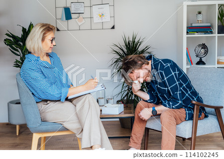 Depressed male patient having psychotherapy session with counselor at mental health clinic. Man with emotional problems consulting professional therapist i comfy office. Psychological help service. Depressed male patient having psychotherapy session with counselor at mental health clinic. Man with emotional problems consulting professional therapist i comfy office. Psychological help service. 114102245