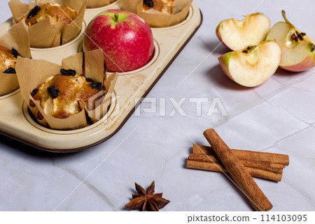 Homemade muffin with apples, raisins and cinnamon sticks. On a light background 114103095