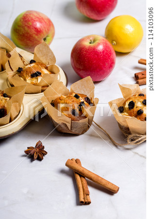 Homemade muffin with apples, raisins and cinnamon sticks. On a light background 114103096
