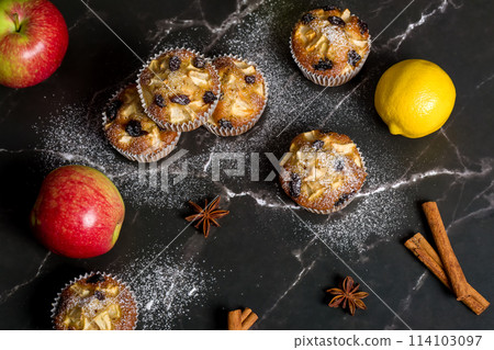 Homemade muffin with apples, raisins and cinnamon sticks. On a dark background 114103097