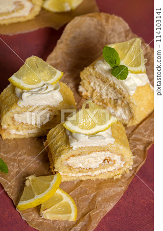 Lemon roll with fruit curd, with mint, close-up. On a burgundy background Lemon roll with fruit curd, with mint, close-up. On a burgundy background 114103141