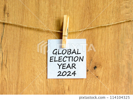 Global election year 2024 symbol. Concept words Global election year 2024 on beautiful white paper on clothespin. Beautiful wooden background. Business Global election year 2024 concept. Copy space 114104325