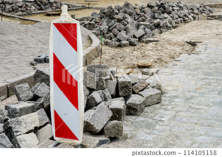 Street paving with historical hammered granite paving stones, city street surface restoration 114105158