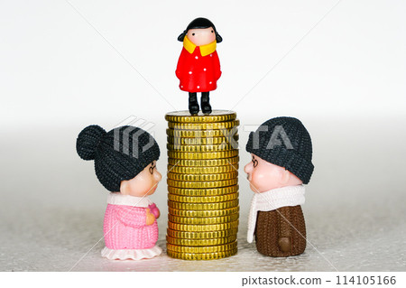 Between mother and father toy figures pile of coins with a child on it, concept of inheritance Between mother and father toy figures pile of coins with a child on it, concept of inheritance 114105166