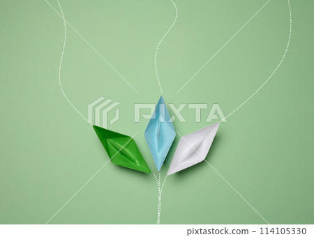 Paper boats on a green background with paths of movement, representing the concept of individuality. Paper boats on a green background with paths of movement, representing the concept of individuality. 114105330