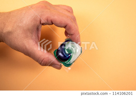 Laundry capsule in hand on light background 114106201
