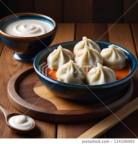 A plate of dumplings alongside a dish of sour cream 114106993