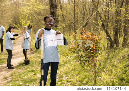 Portrait of african american girl holding banner with save our planet message, spreading ecological justice and awareness. Teenager activist posing with a poster to fight environmental pollution. Portrait of african american girl holding banner with save our planet message, spreading ecological justice and awareness. Teenager activist posing with a poster to fight environmental pollution. 114107144