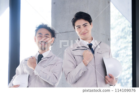 Two handsome workers with helmets. Image of building construction management, maintenance inspection, etc.. Fist pump 114109076