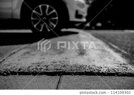 Selective focus on area in front of a speed bump with a car driving over. Selective focus on area in front of a speed bump with a car driving over. 114109302