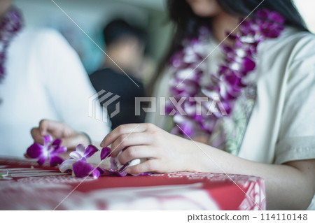 Young people experiencing orchid lei making in Waikiki, Hawaii 114110148