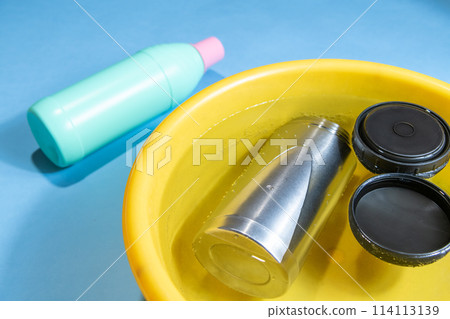 在漂白和消毒過程中將水瓶浸入廚房漂白劑中。 114113139