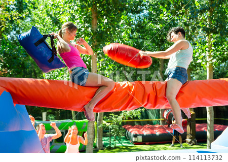 Women having pillow fight between each other in outdoor amusement park Women having pillow fight between each other in outdoor amusement park 114113732