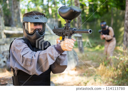 Paintball player recklessly aims with a gun on battlefield Paintball player recklessly aims with a gun on battlefield 114113780