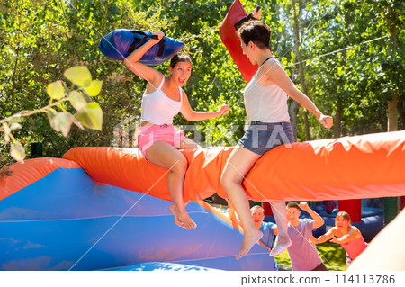 Women holding soft pillows and fighting in adventure park Women holding soft pillows and fighting in adventure park 114113786