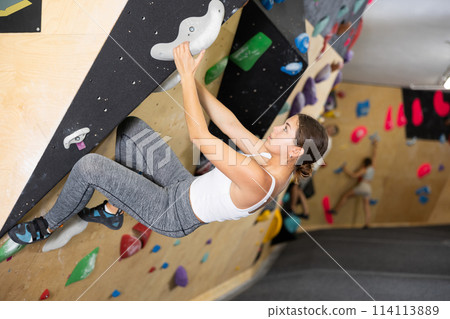 Young woman practicing rock climbing on climbing wall 114113889