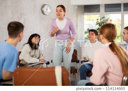 Young woman teacher conducting lesson with group of students Young woman teacher conducting lesson with group of students 114114003