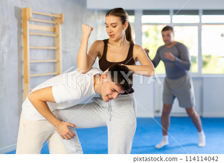 Young woman and guy training self-defense techniques 114114042