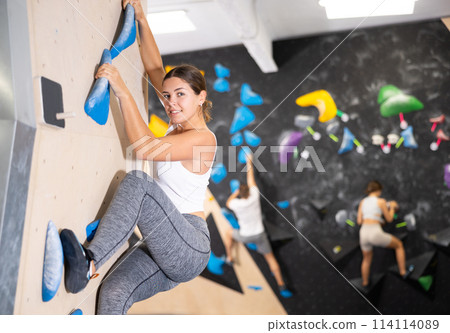 Young woman practicing rock climbing on climbing wall Young woman practicing rock climbing on climbing wall 114114089