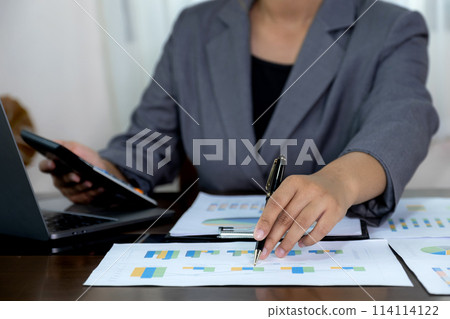 Businesswoman hand holding pen, analysis the graph with laptop at the home office for setting challenging business goals And planning to achieve the new target 114114122