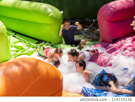 Happy friends collecting ball in foam pool in outdoor playground Happy friends collecting ball in foam pool in outdoor playground 114114136